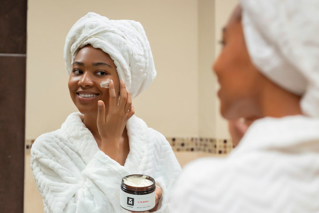 A woman applying moisturizer to her cheek.