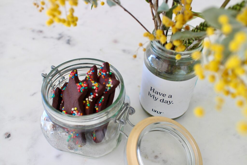 A jar of cookies next to a flower vase.