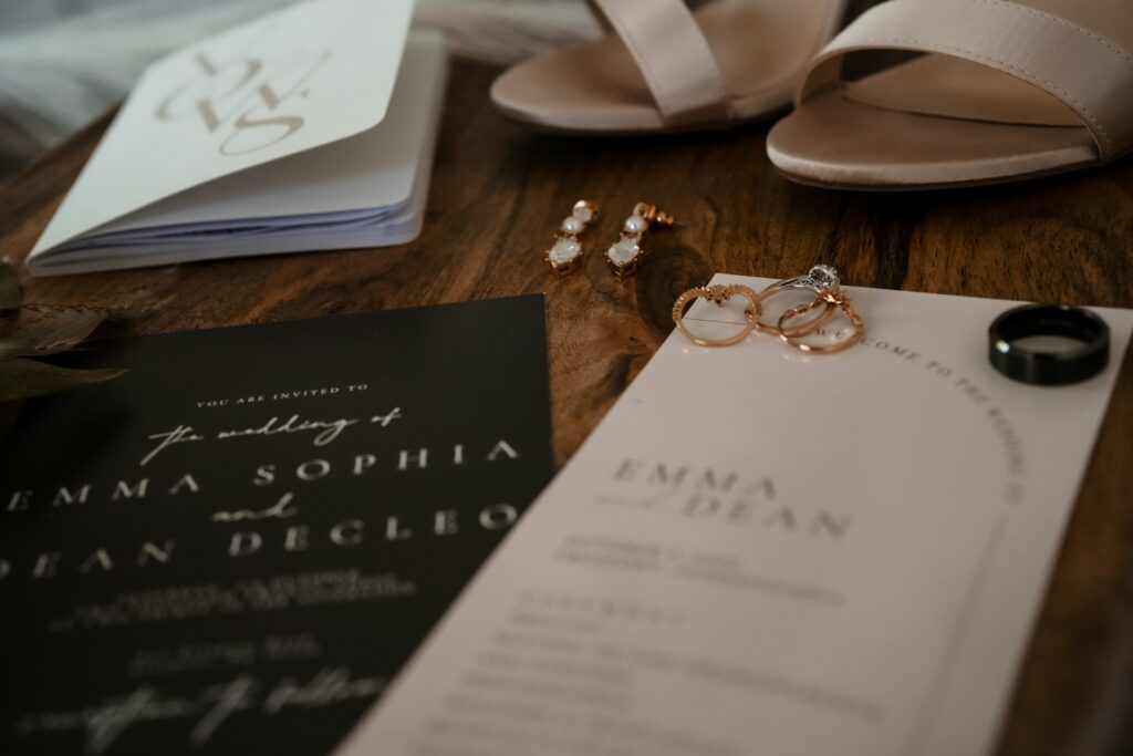 A black wedding invitation, wedding heels and jewelry, including rings and earrings