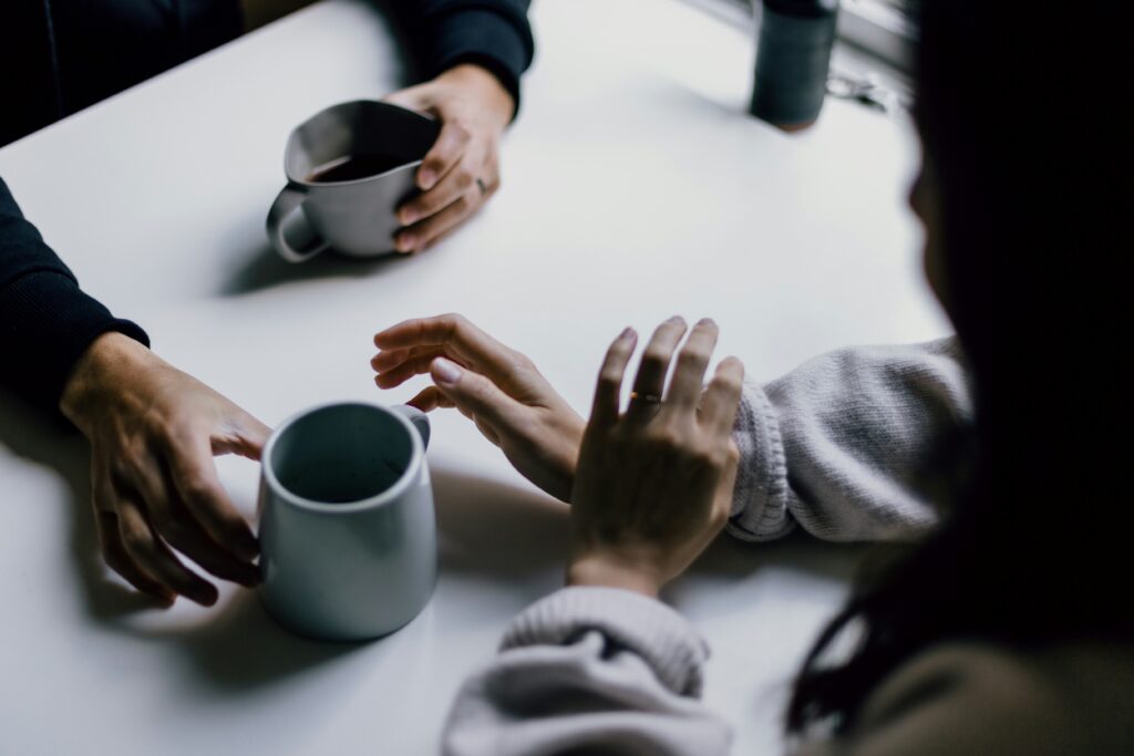 Two people sitting across a table drinking coffee.