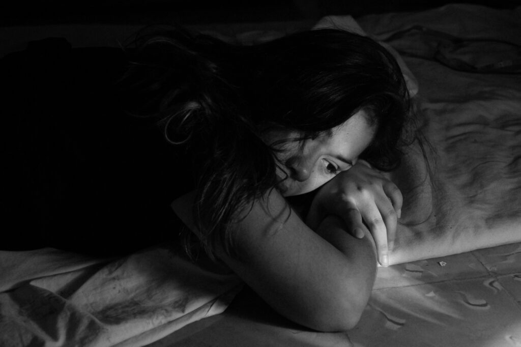 A woman lying down with a sad expression.
