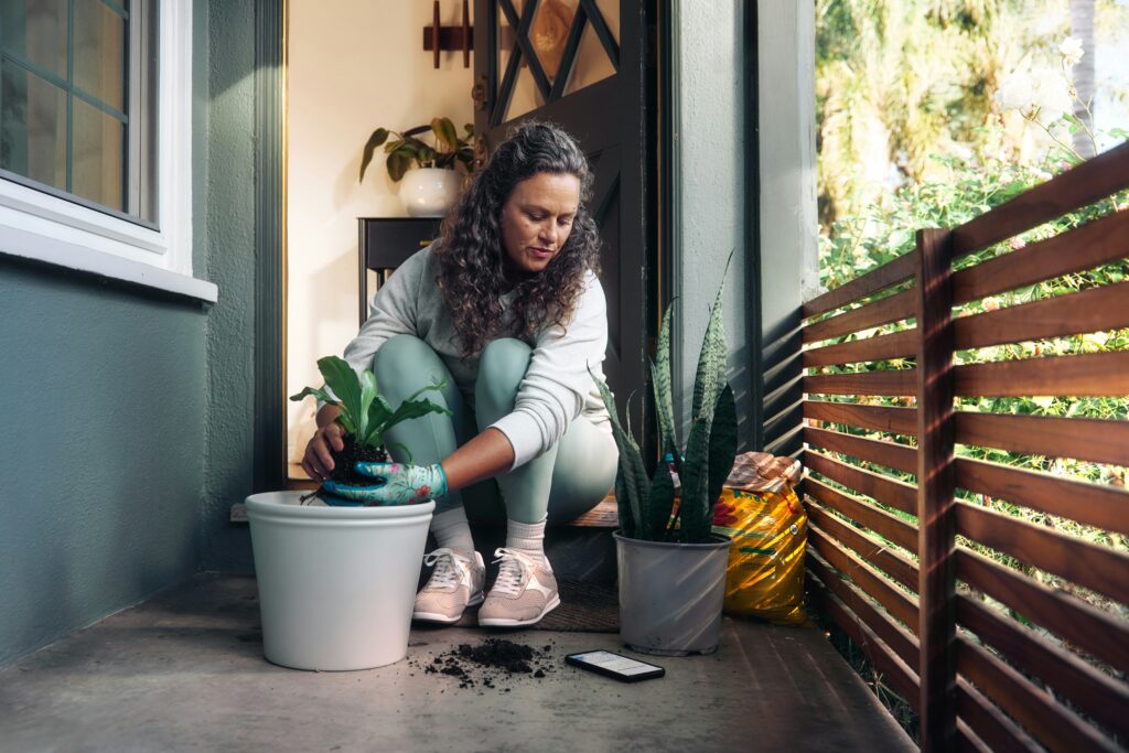 A woman putting a plant in a pot.