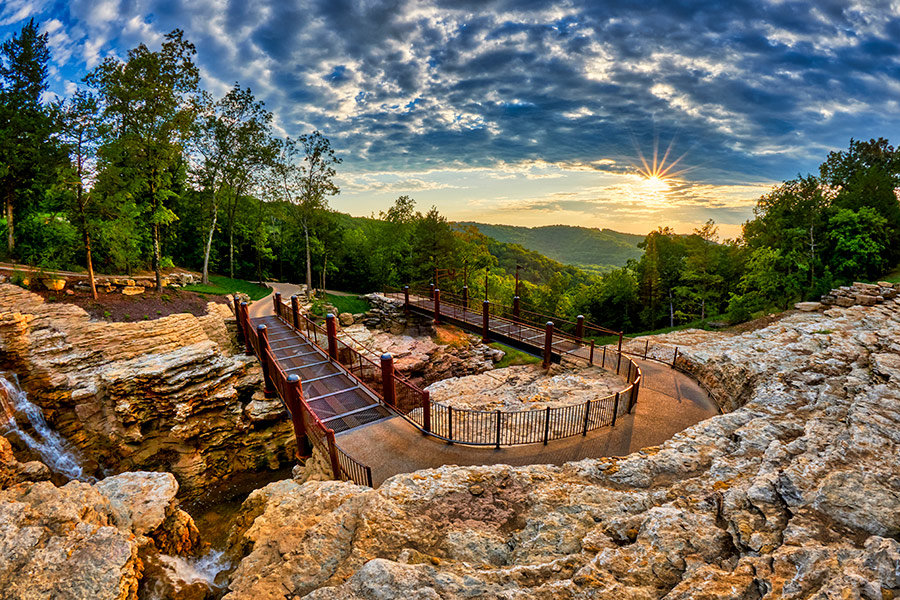 Big Cedar Lodge's walking path sits on a cliff side under a blue, cloudy sky.