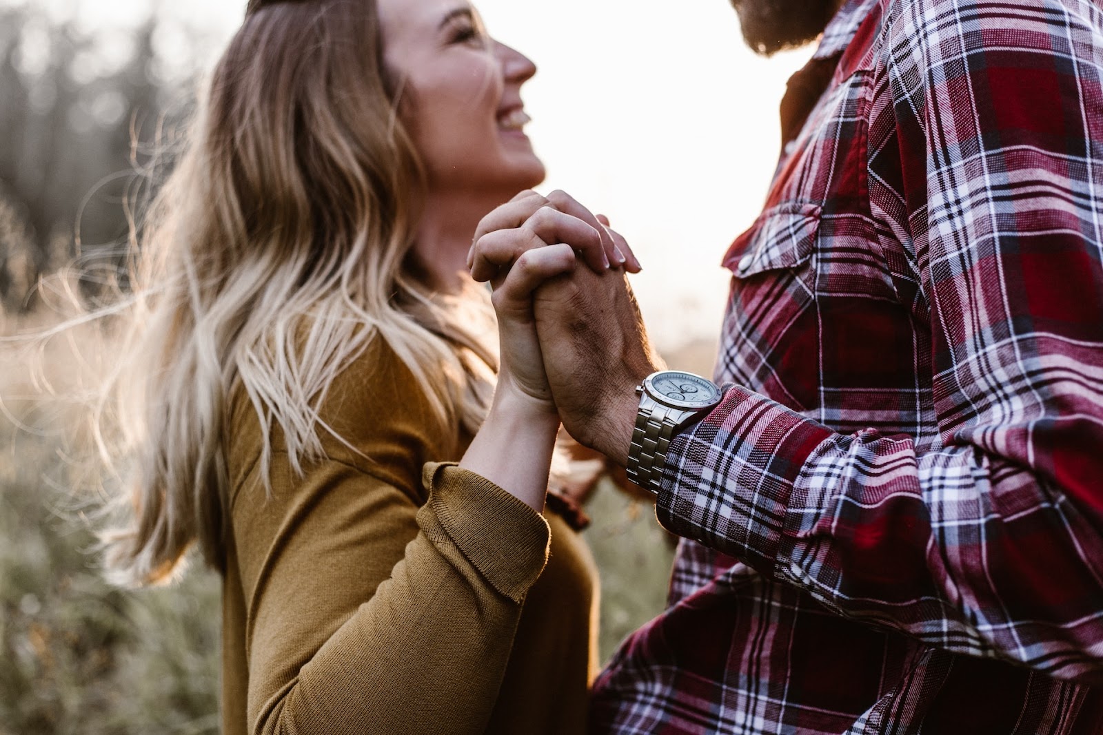 A couple holds hands, the woman smiling at her partner