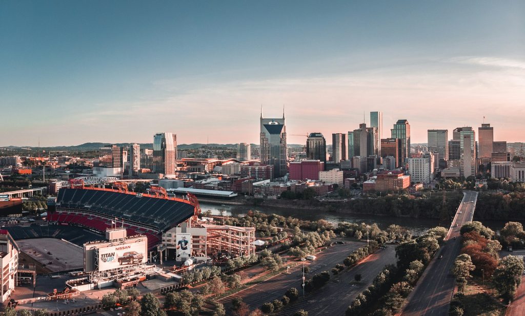 The Nashville skyline sits under a blue sky. Nissan Stadium is in front of it. It's one of the birthday trip ideas people consider before traveling for their big day.