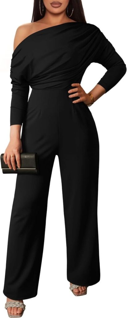 A woman stands in a black jumpsuit that hangs off one shoulder.
