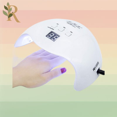 A UV LED lamp designed to dry gel nail polish sits against the Revivalist branded background of pink, orange, yellow and green stripes. Someone's hand sits under it to dry their red gel polish.