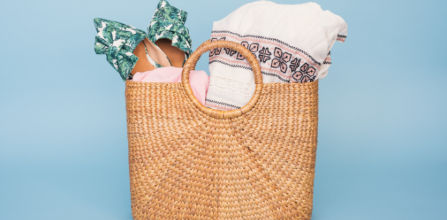 A woven basket is filled with clothing and shoes.