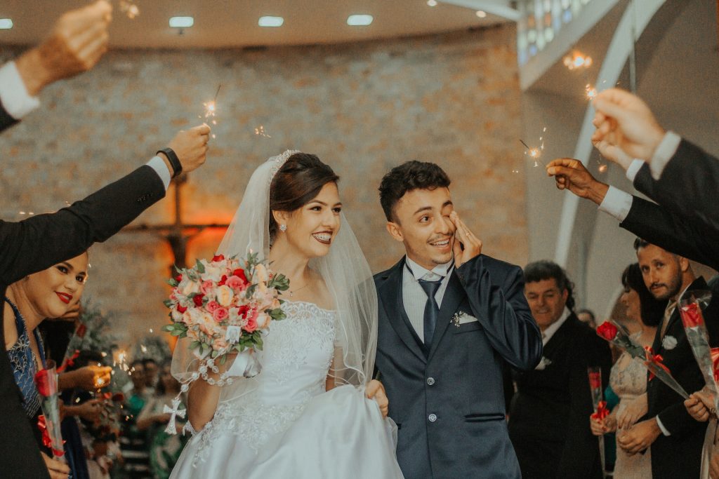 A bride and groom exit a church as guests hold up sparklers.