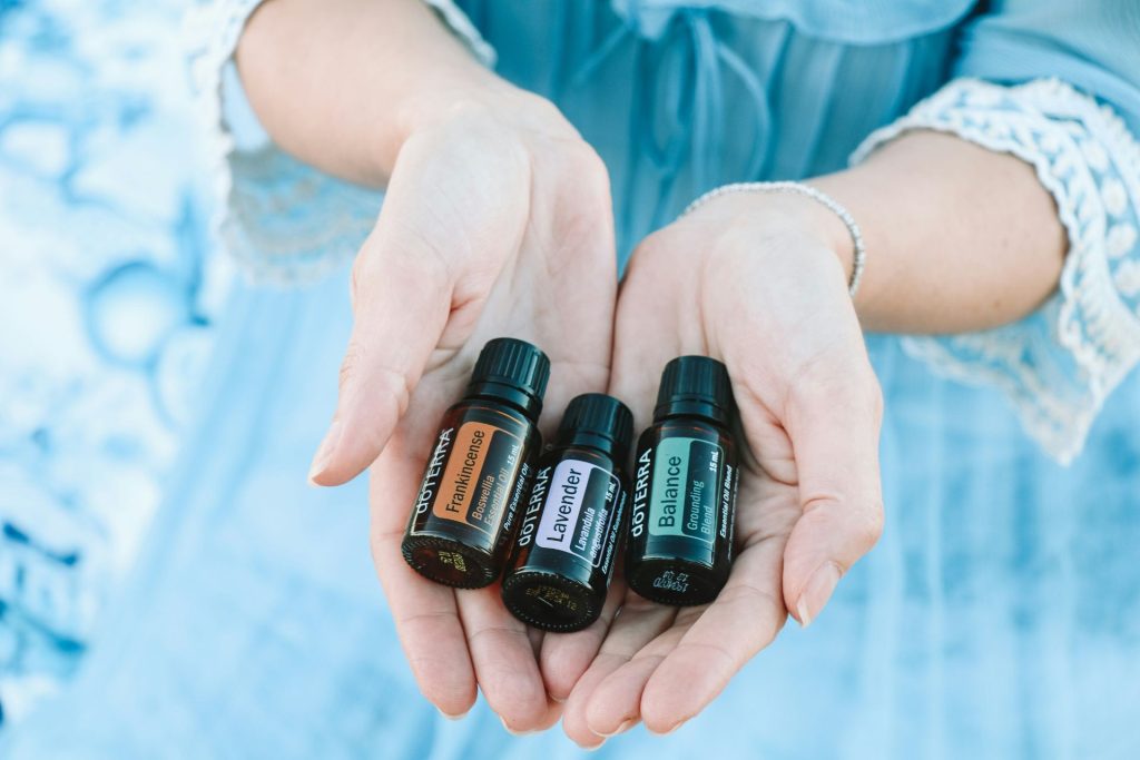A person in a blue dress with three doTERRA essential oils laying in both hands