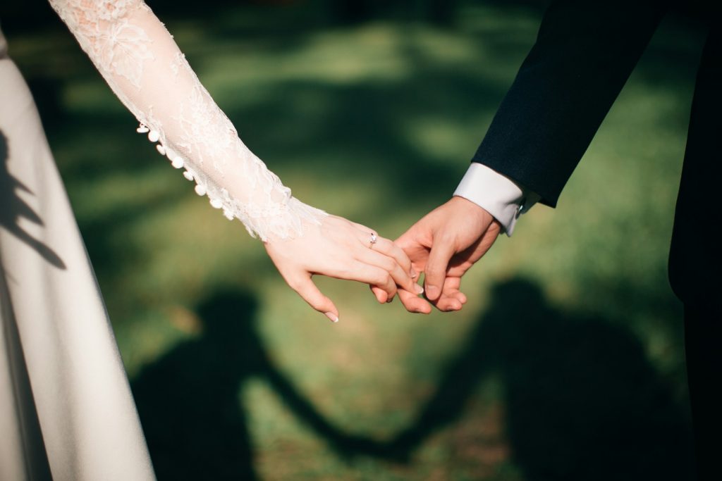 A bride and groom hold hands.