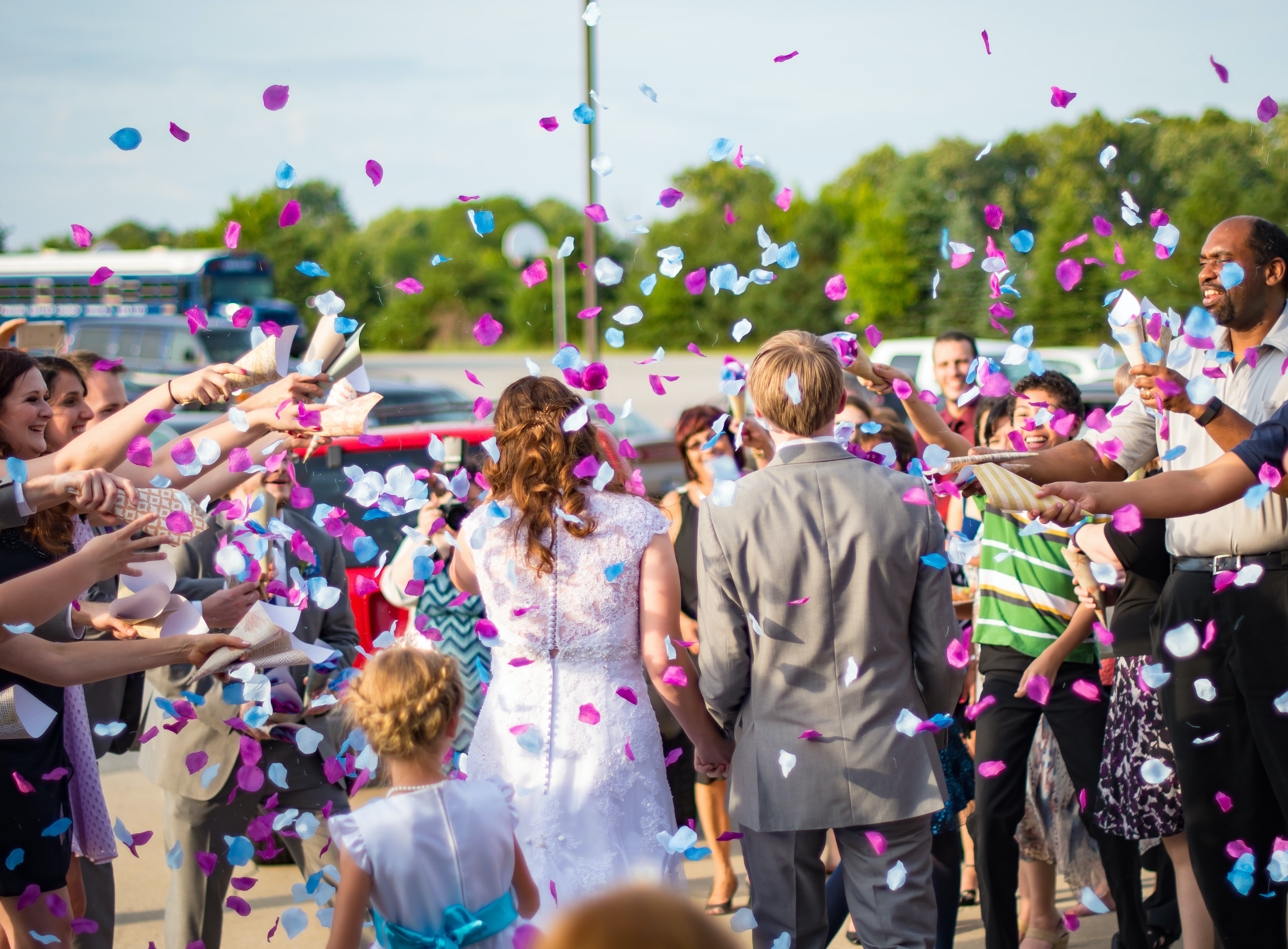 Wedding guests throw confetti as the bride and groom walk by.