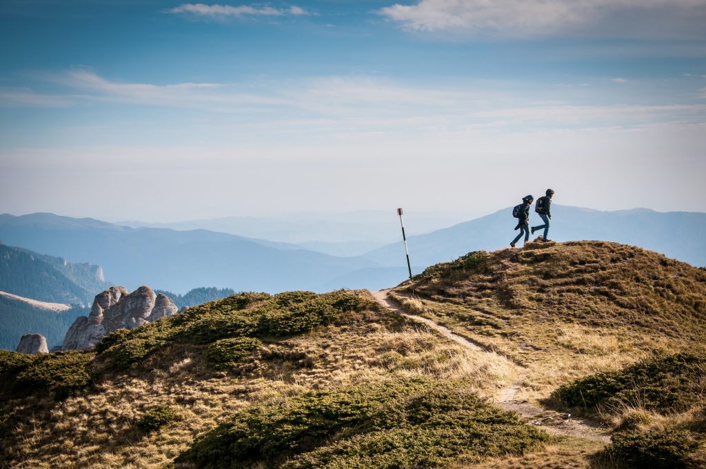 Two people walk along a cliff side.