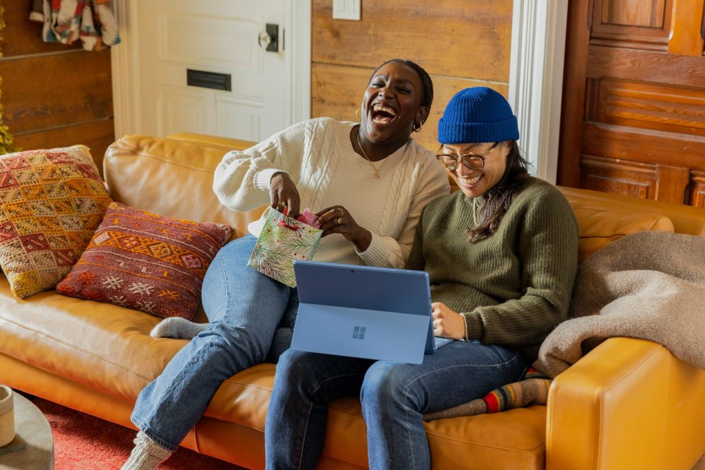 Two people laughing while looking at a tablet.