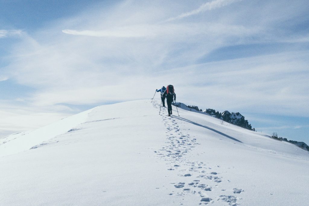 People climbing a mountain in the snow.
