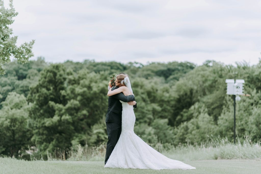 A bride hugs her father at an outdoor wedding.