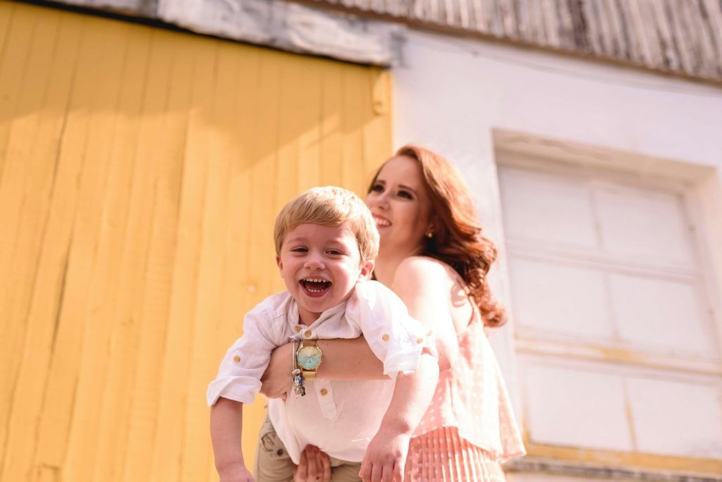A mother holding her laughing son.