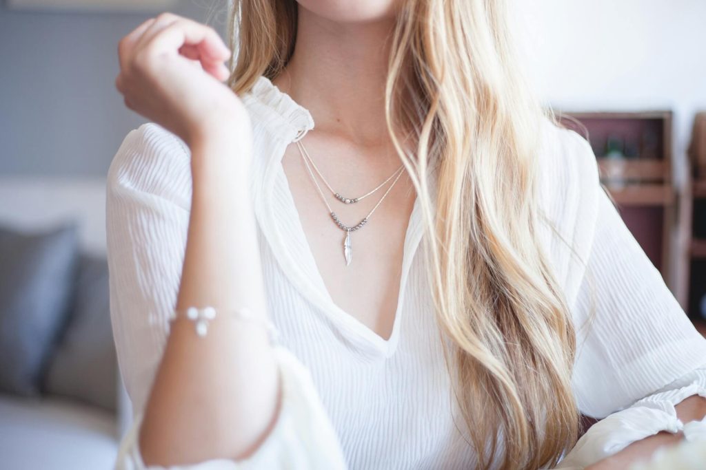 A woman wearing silver necklaces and a bracelet.