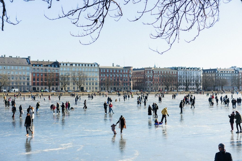 An iceskating rink filled with people in front of a row of buildings