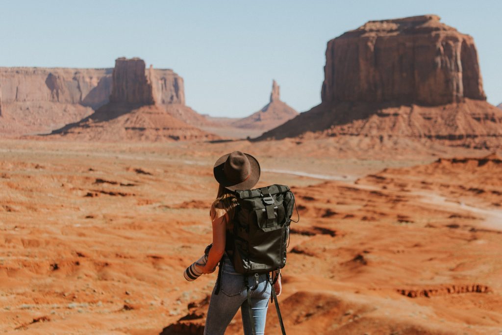 A woman with a camera stands in front of a mountain.