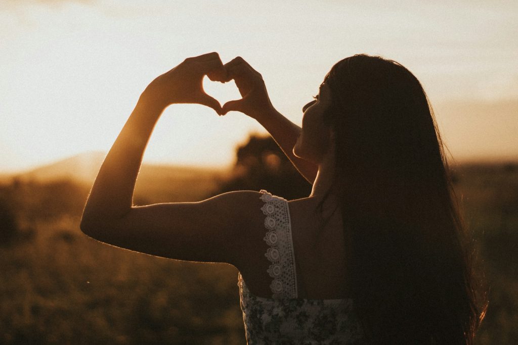 A woman making a heart with her hands.