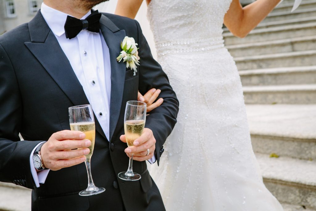 A bride wears a beaded dress, standing next to a groom.
