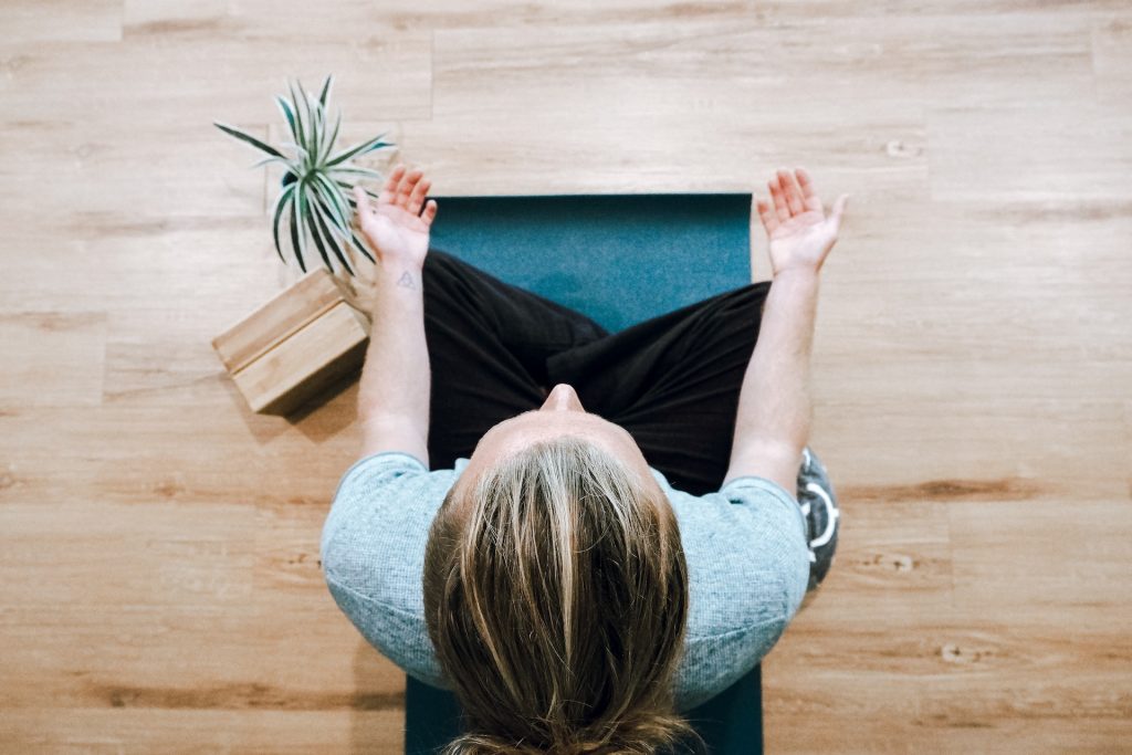 A woman sits cross-legged with her palms up.