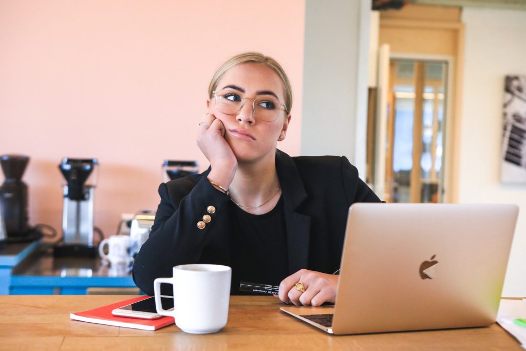 A woman sits at a desk appearing to be deep in thought.