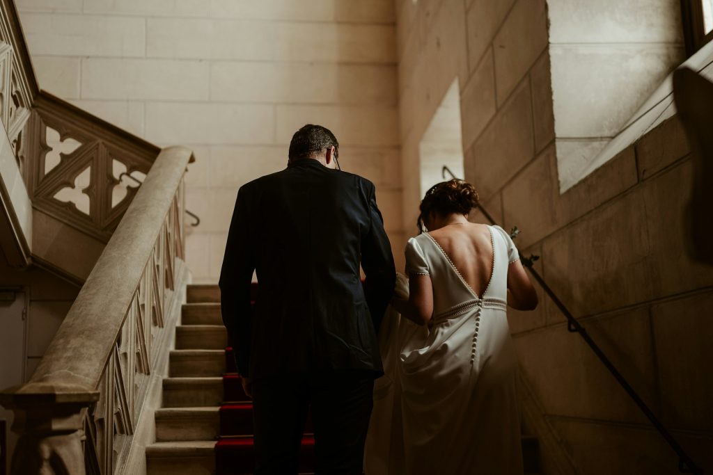 A man and woman walk up the stairs in a historic building.