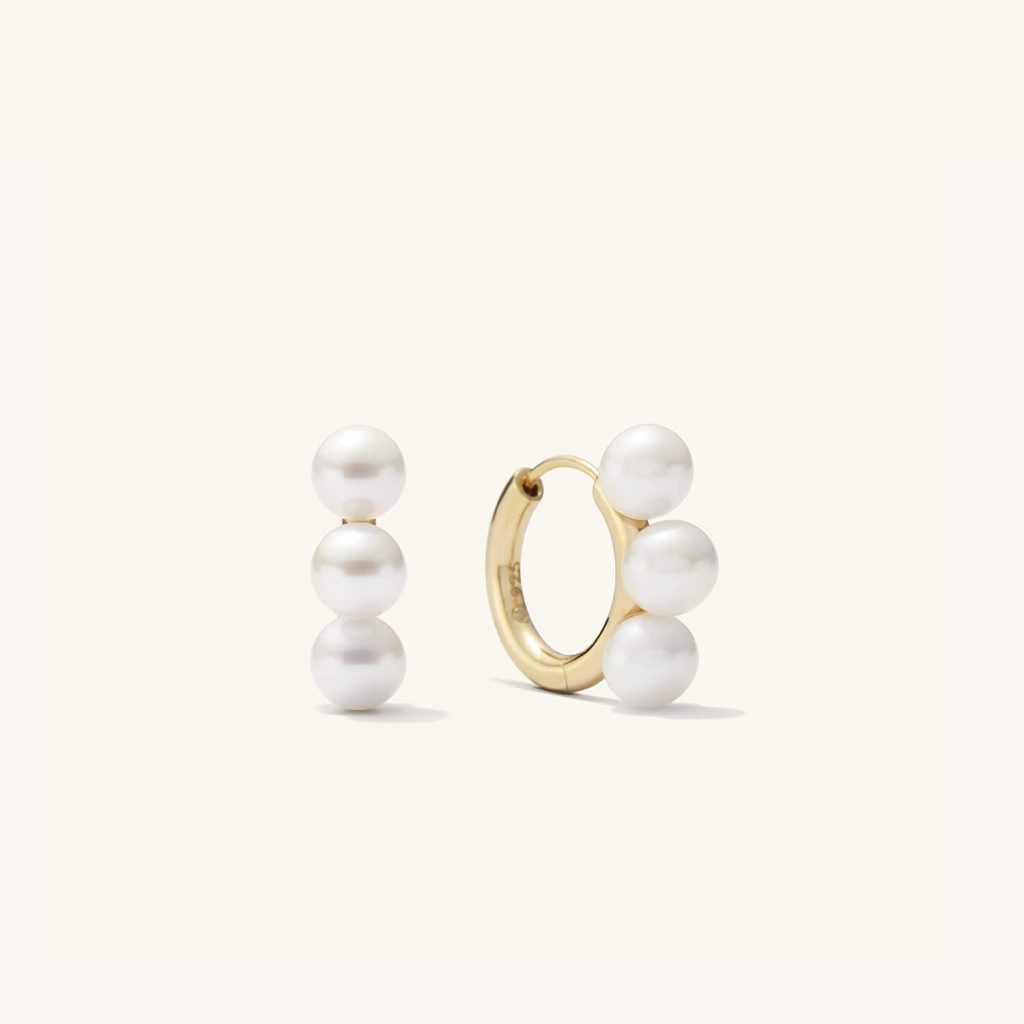 Gold hoop earrings lined with three pearls.