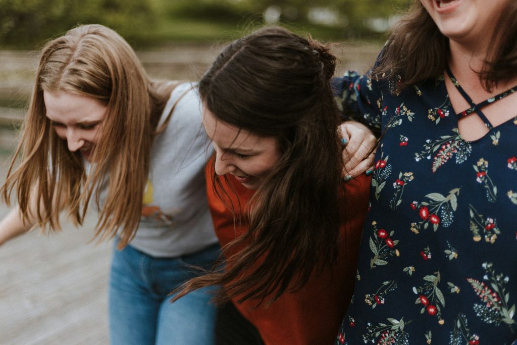 Three women walk with their harms around each other.