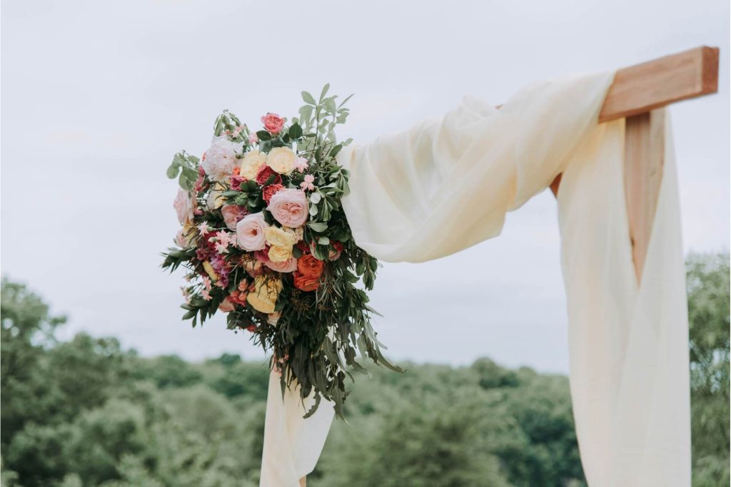 A flower bouquet attached to a wooden structure draped in linen.