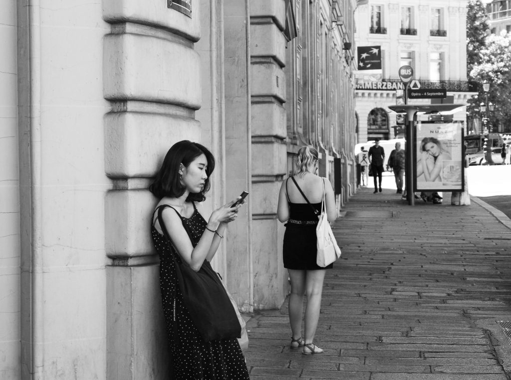 A woman in a polka dot dress leans against a wall.