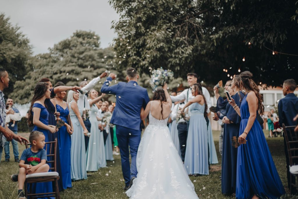 Wedding guests throw confetti as the bride and groom walk by.