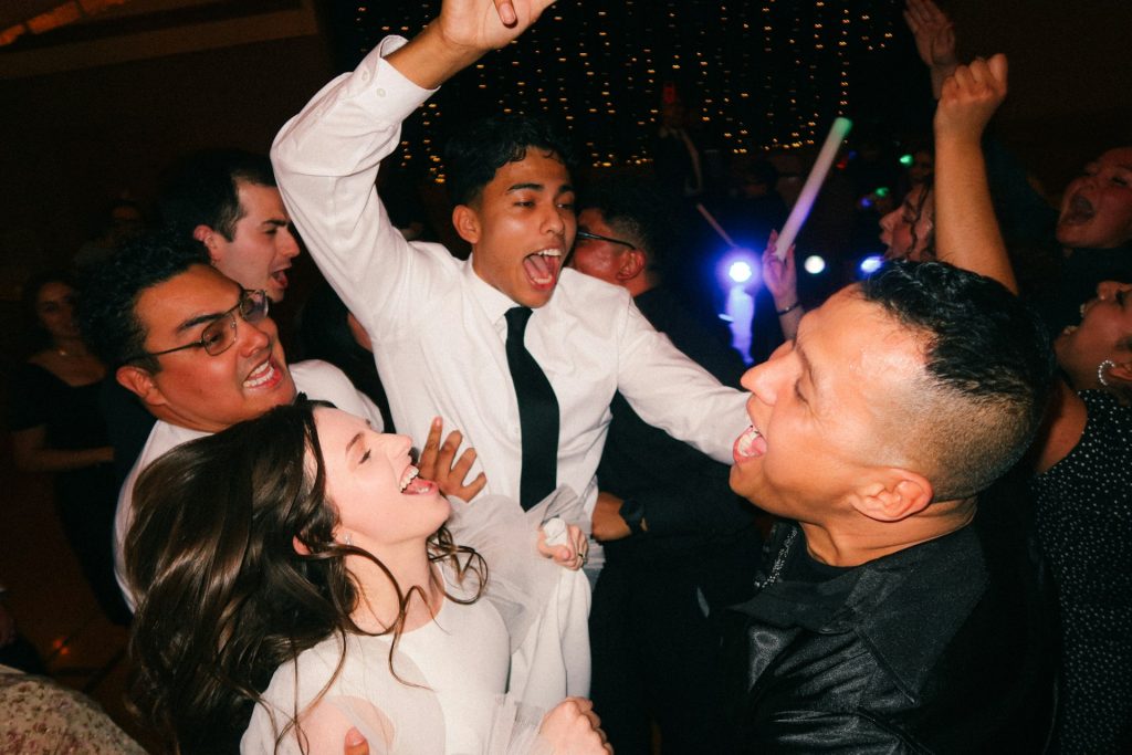 A bride, groom and groomsmen dance at a wedding reception.