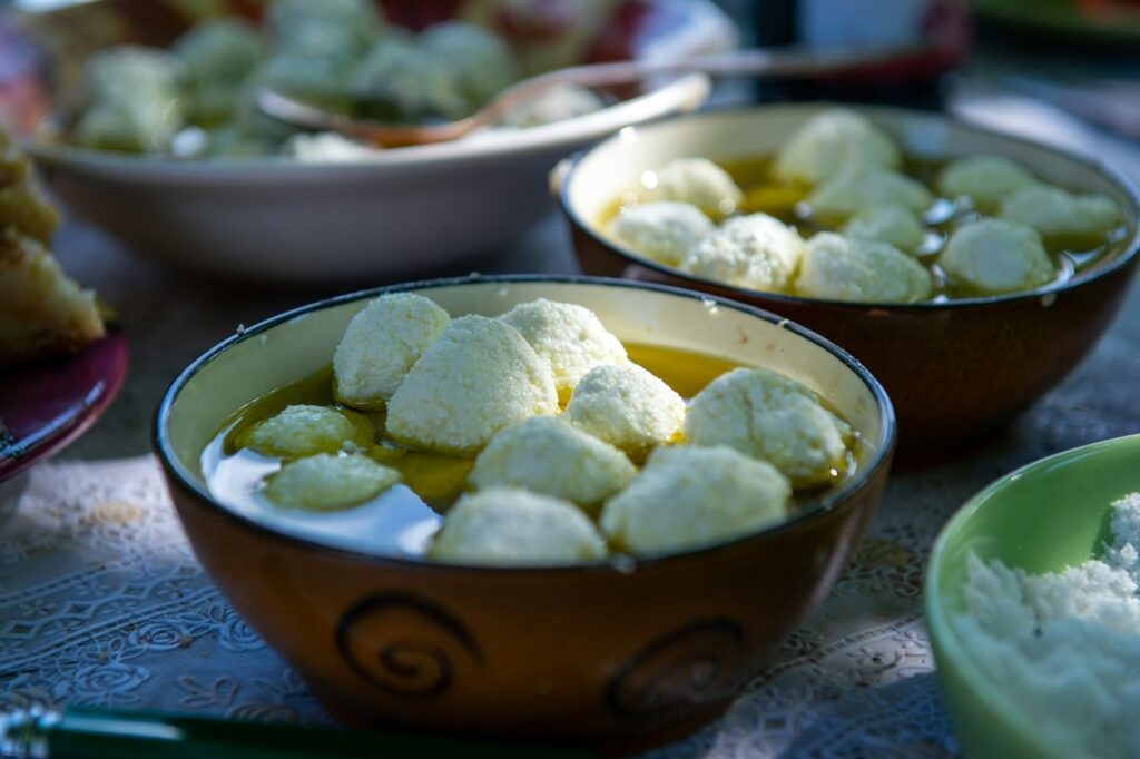 Bowls of white cheese curds soaking in olive oil. The setup is outdoors on a patterned tablecloth, evoking a rustic and inviting atmosphere.