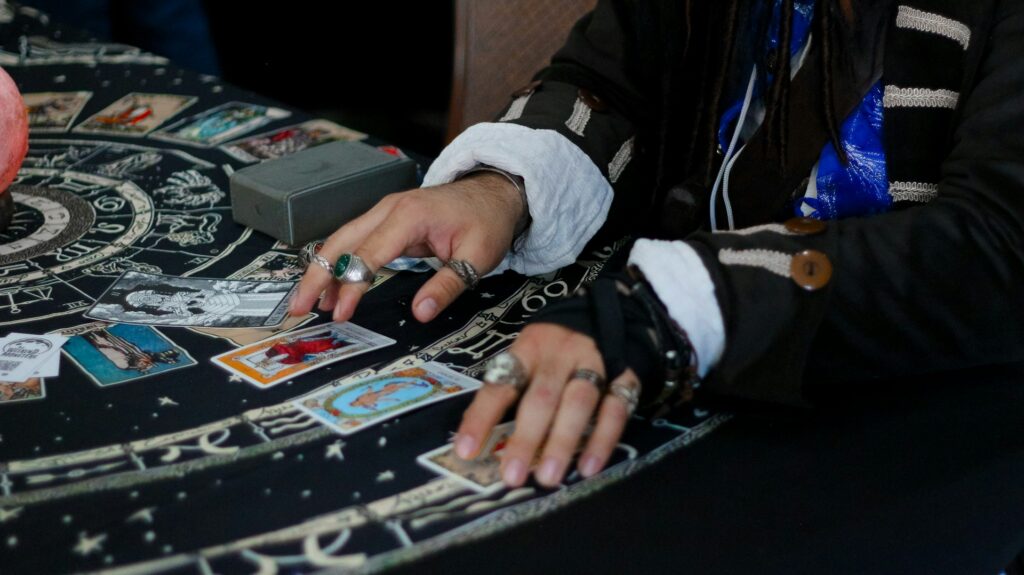 Hands arranging tarot cards on a celestial patterned cloth.