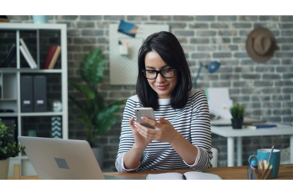 A woman using her phone and laptop at the same time