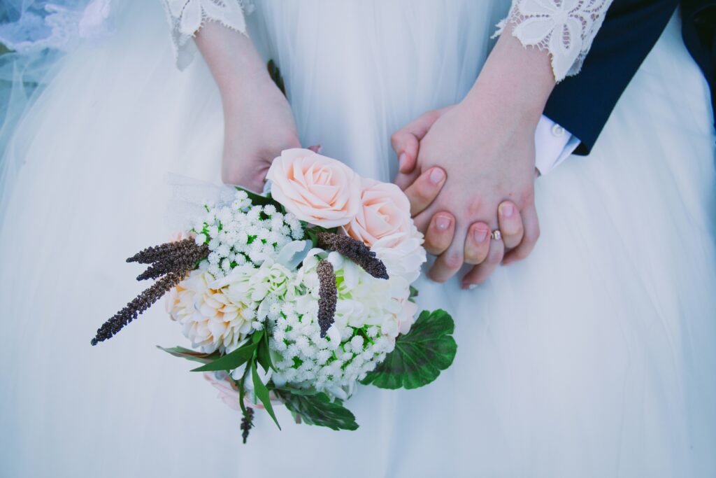 couple holding hands and wedding bouquet