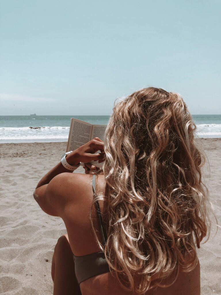 A girl on the beach reading a book