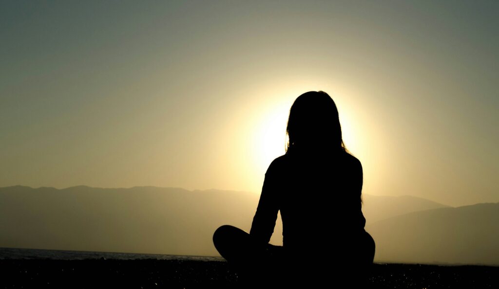Woman sitting on sand sunrise