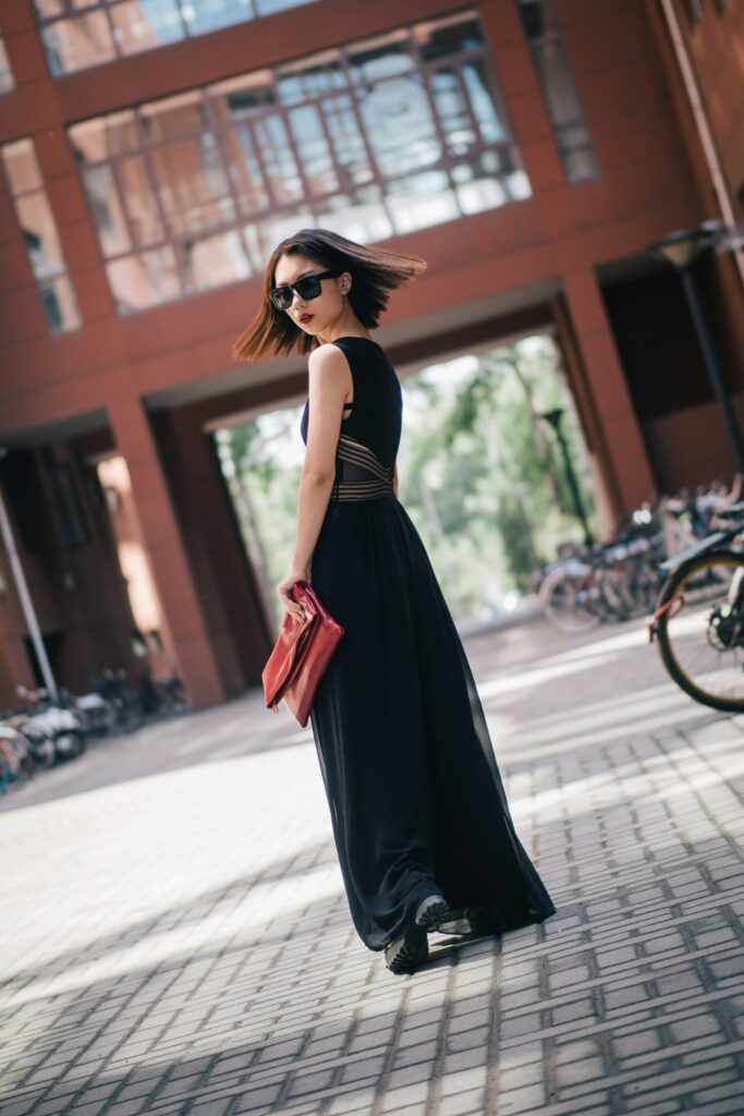 woman in black dress and sunglasses holding a red purse
