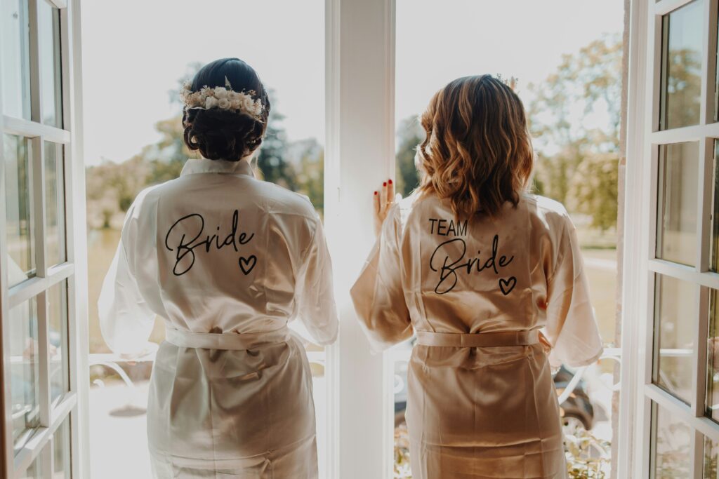 Bride in robe next to bridesmaid in matching robe