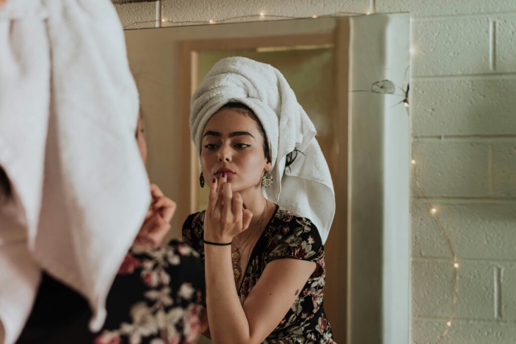 Woman looking in mirror with towel on her head