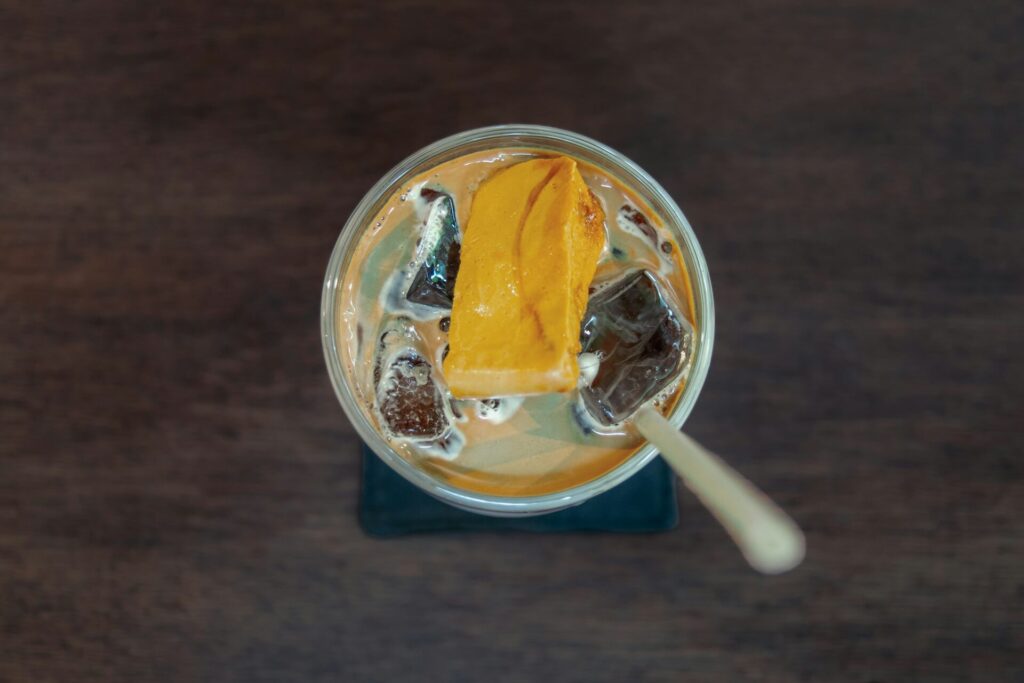 Iced coffee served in a clear glass with cream and a straw
