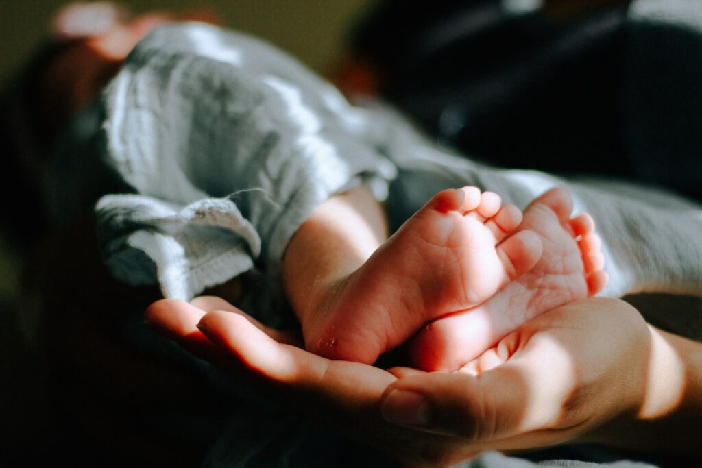 Adult hands cradling a newborn baby's tiny feet