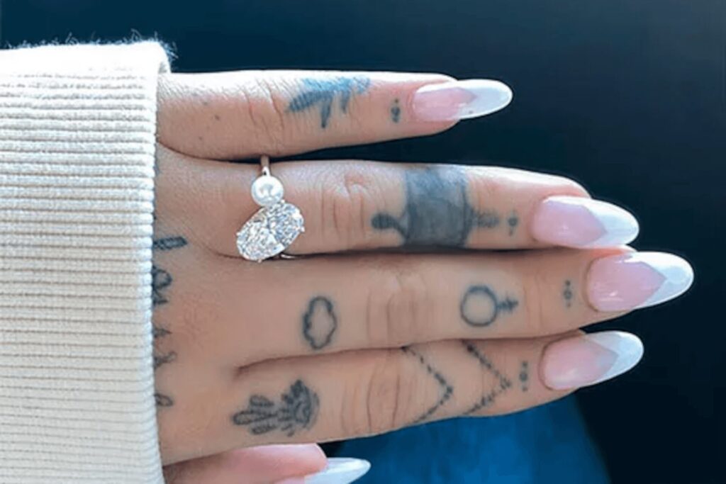 A close-up of Ariana Grande's pearl and diamond engagement ring on her finger