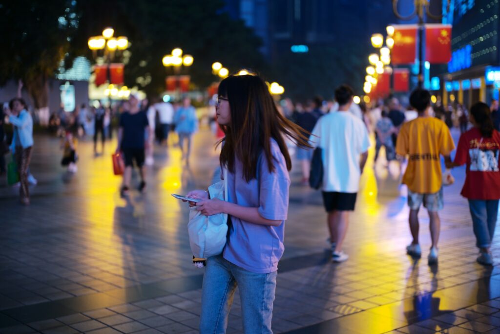 woman in the middle of a city with her phone and people surrounding her