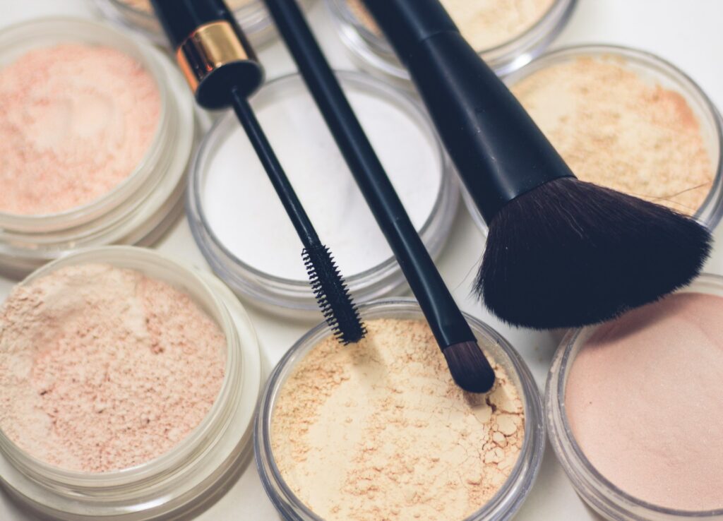 A collection of makeup brushes alongside jars of loose powder, arranged neatly on a vanity surface.