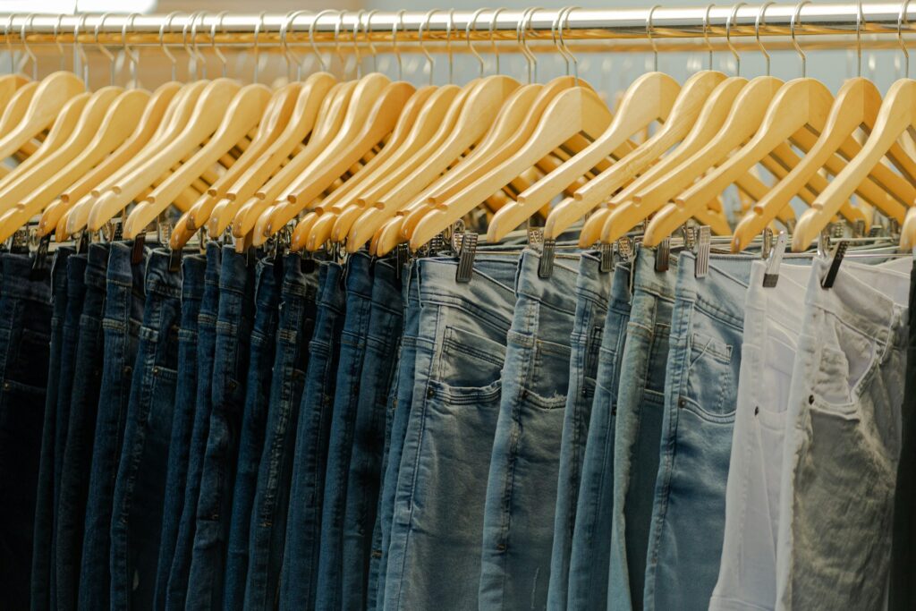 A wide variety of jeans of different washes all lined up in hangers